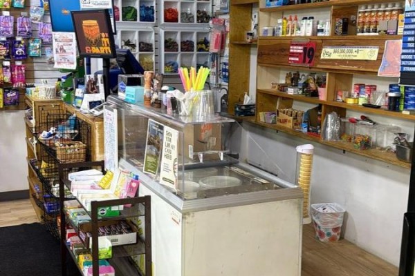 Interior view of a store counter with an ice cream freezer and shelves of goods. - 1 - 1648 Taunton Rd Road E, Clarington