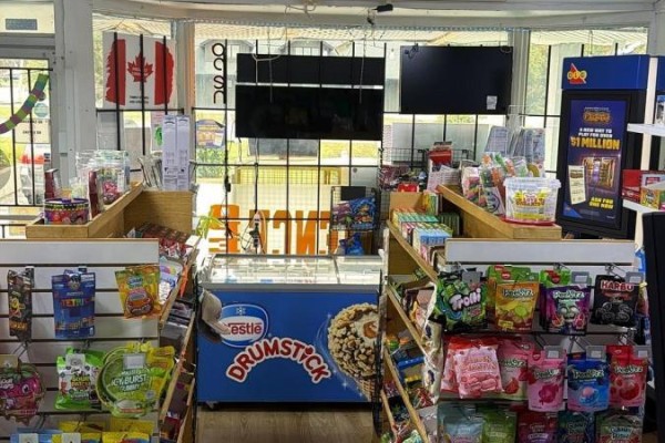 View of store aisles with candy, snacks, and beverage coolers visible through the front window. - 1 - 1648 Taunton Rd Road E, Clarington