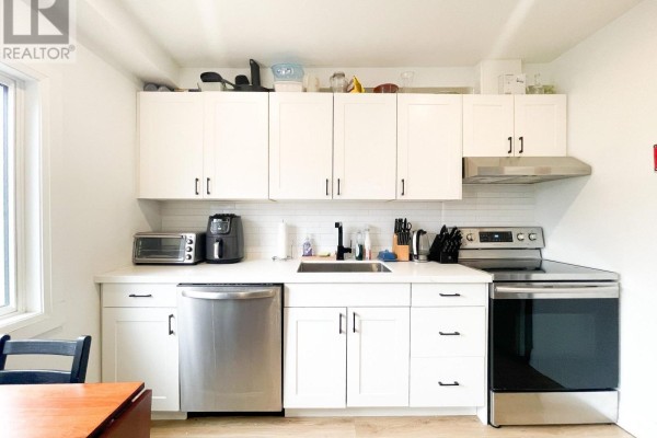Close-up of white kitchen cabinets, stainless steel appliances, and a black sink. - 1 - 20 Sullivan Street, Toronto