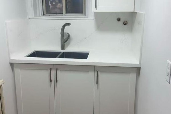 Kitchenette area with a white double sink, chrome faucet, and white cabinets. - 1 - 202 O'connor Drive, Toronto
