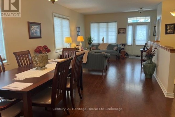 Dining room with a dark wood table and chairs, flowing into the living room and entryway. - 1 - 21 Balazs Court, Tillsonburg