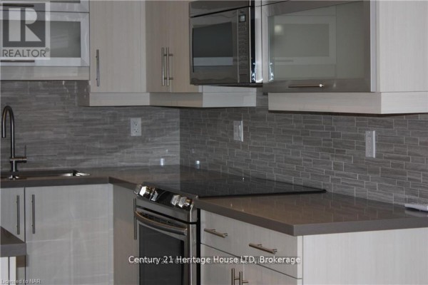 Tiled hallway with grey rectangular tiles, flush ceiling lights, and a fire alarm. - 1 - 238 Bertie Street, Fort Erie