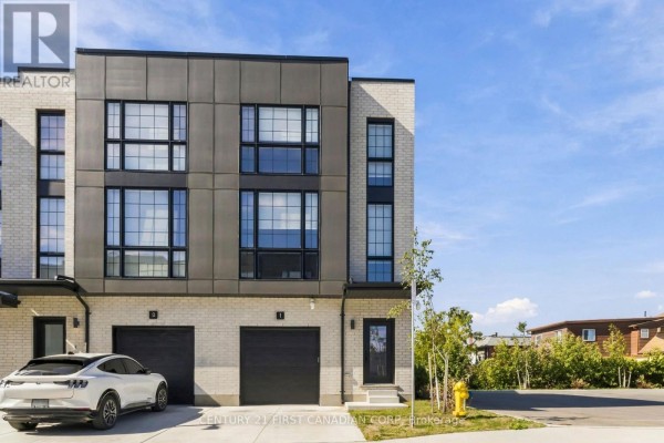 Front exterior of townhouse unit 1, showing a garage door and entryway. - 1 - 2500 Main Street, London South
