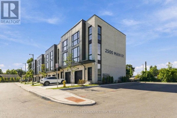 Side exterior view of the townhouse complex, showing multiple units and street. - 1 - 2500 Main Street, London South