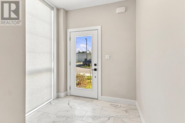 Interior hallway with a glass door leading outside and marble tile flooring. - 1 - 2500 Main Street, London South