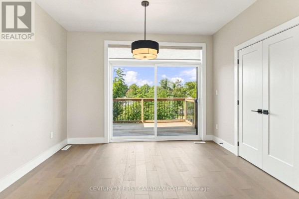 Living area with hardwood floors, a large sliding glass door, and a deck. - 1 - 2500 Main Street, London South