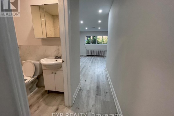 Hallway view towards a bathroom and a brightly lit room with windows. - 1 - 259 Lakeshore Road E, Mississauga
