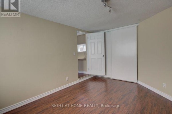 Bedroom with wood laminate flooring, beige walls, and a sliding door closet. - 1 - 26 Victoria Street, Toronto
