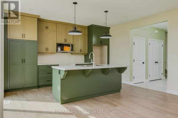 Kitchen with two-tone green and beige cabinets, a marble-topped island, and pendant lights. - 1 - 278 Mary Rose Avenue, Saugeen Shores