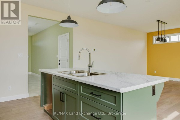 Kitchen island with a double sink and faucet, facing an open doorway and a yellow wall. - 1 - 278 Mary Rose Avenue, Saugeen Shores