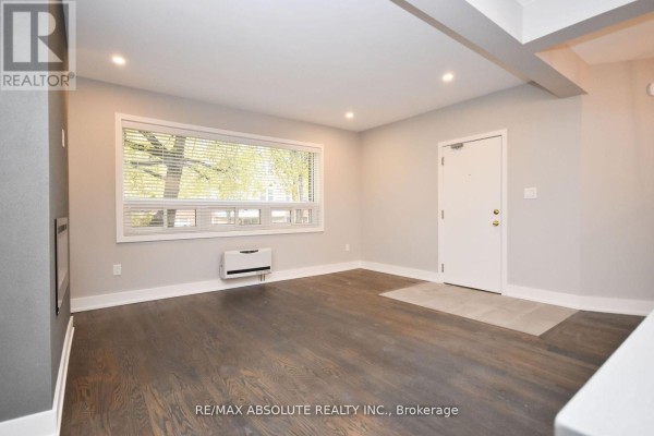 Living room with dark wood floors, large window, and white door. - 1 - 280 Daly Avenue, Ottawa