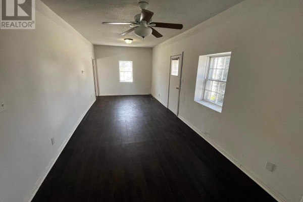 Living room with dark wood floors, white walls, ceiling fan, and two windows. - 1 - 29 Rykert Street, St  Catharines