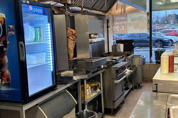 Kitchen counter with shawarma spit, grills, and beverage cooler, viewed from dining area. - 1 - 31 Tapscott Road, Toronto