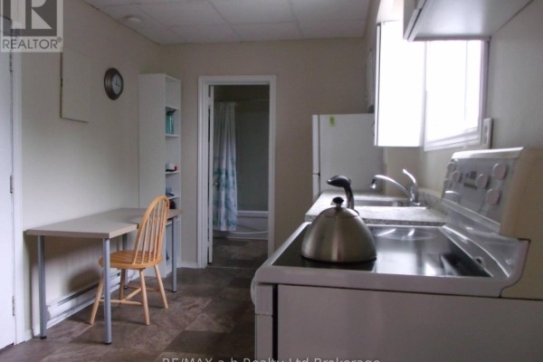 A kitchen with a stove, sink, and refrigerator, with a doorway showing a bathtub. - 1 - 350 Dundas Street, Woodstock