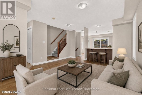 Living room with beige sofa, chairs, wood coffee table, and staircase. - 1 - 37 Silver Street, Huntsville