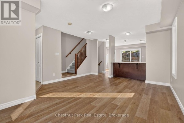 Living room with wood floors, staircase, and dark wood breakfast bar with stools. - 1 - 37 Silver Street, Huntsville