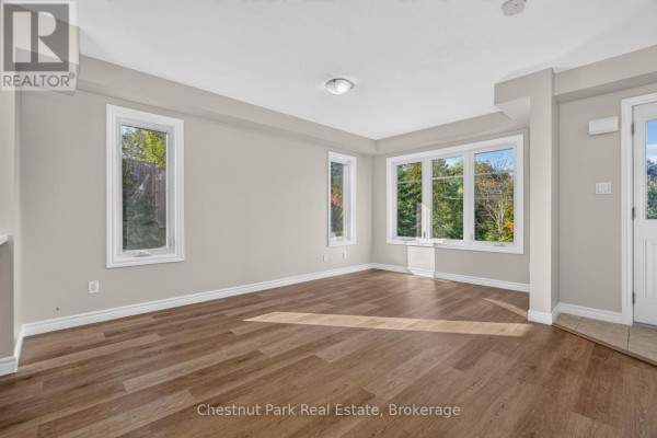 Bright living area with wood floors, large windows facing trees, and glass door. - 1 - 37 Silver Street, Huntsville