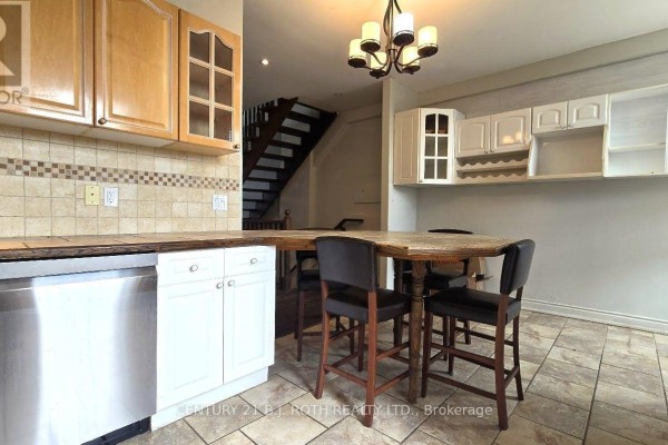 Kitchen with pantry cabinets, island seating, and view of staircase. - 1 - 41 Dunlop Street E, Barrie