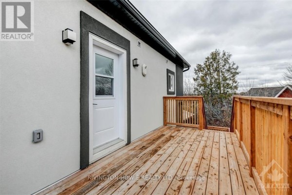 Wooden deck with railing attached to a building exterior, accessible by stairs. - 1 - 413 Donald B Munro Drive, Ottawa