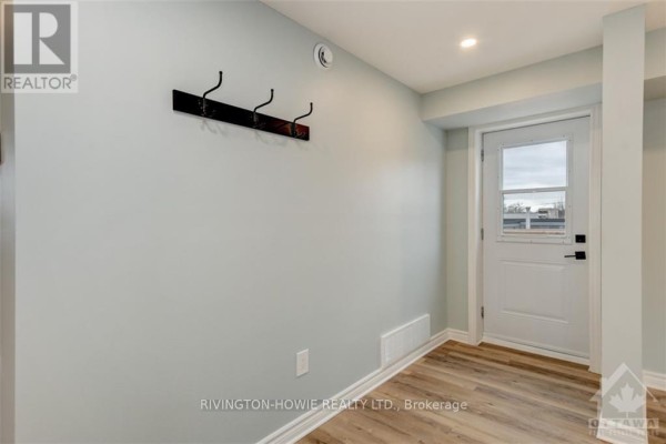 Interior hallway with a white door, coat rack on a light blue wall, and light wood laminate flooring. - 1 - 413 Donald B Munro Drive, Ottawa
