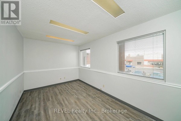 Empty office room with light grey walls, white trim, and wood-look laminate flooring. - 1 - 437 Welland Avenue, St  Catharines