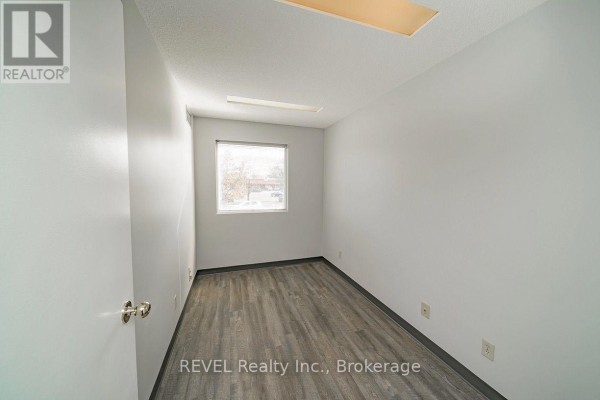 Empty office with light grey walls, white trim, and wood-look laminate flooring. - 1 - 437 Welland Avenue, St  Catharines