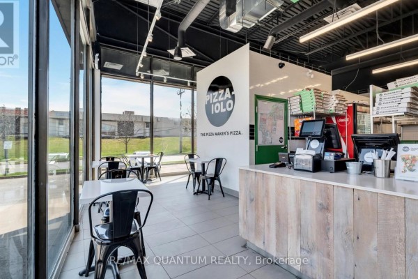 Interior dining area with tables and chairs next to large windows overlooking the exterior. - 1 - 4700 Dufferin Street, Toronto