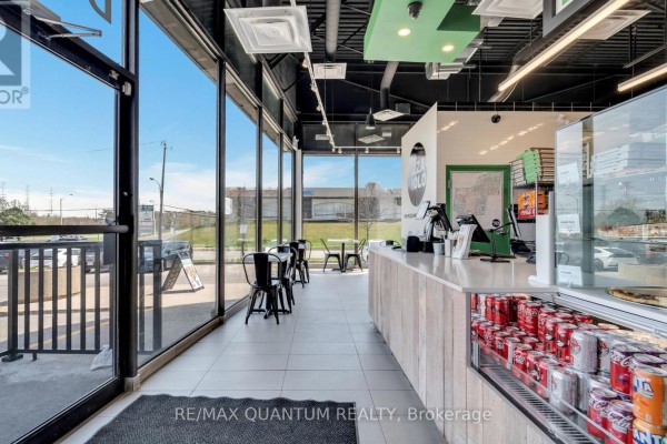 View of the pizza restaurant interior with seating, counter, and large glass windows facing outside. - 1 - 4700 Dufferin Street, Toronto