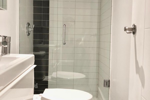 White tiled shower with glass door and chrome fixtures in a bathroom. - 1 - 50 Pape Avenue, Toronto