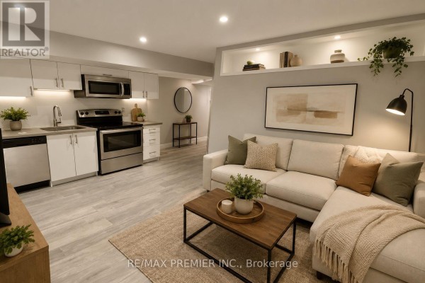 Living area with sectional sofa, coffee table, and adjacent kitchen with stainless steel appliances. - 1 - 50 Pape Avenue, Toronto