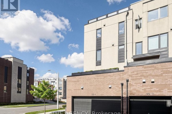 Close-up exterior view of modern townhouses with beige siding and brick, showing garages. - 1 - 55 Thomas Mulholland Drive, Toronto
