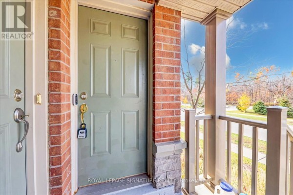 Close-up of the light green front door of a townhouse with brick and stone accents. - 1 - 5625 Oscar Peterson Boulevard, Mississauga