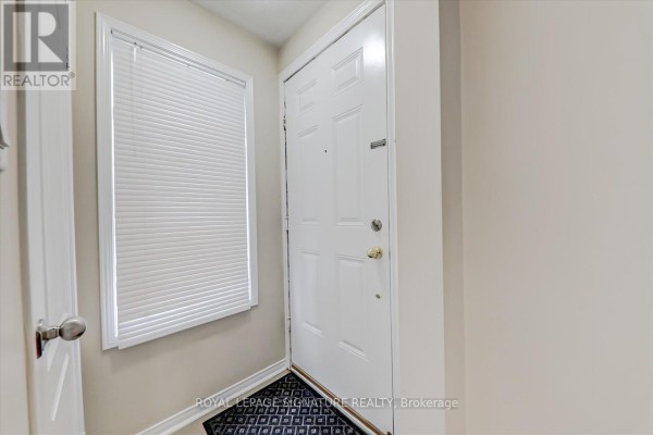 Interior view of a white front door with a pleated window blind to the left. - 1 - 5625 Oscar Peterson Boulevard, Mississauga