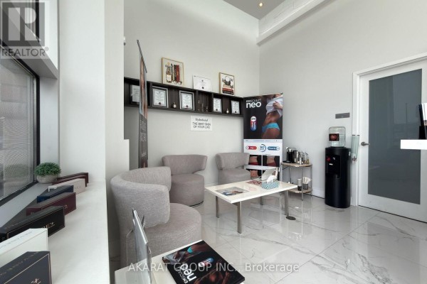 Waiting area with modern grey armchairs, a white coffee table, and framed certificates. - 1 - 5985 Steeles Avenue E, Toronto