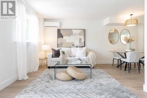 Living room with a white sofa, glass coffee table, and beige rug. - 1 - 684 Dynes Road, Burlington