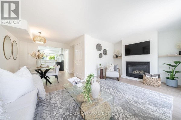 Living room with a fireplace, wall-mounted television, and dining area beyond. - 1 - 684 Dynes Road, Burlington