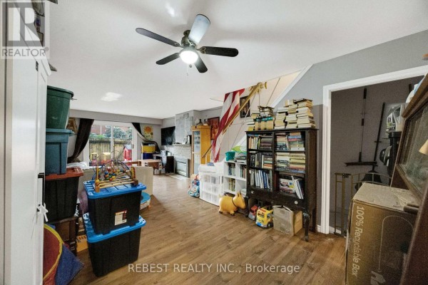 Living area with wood-look flooring, furniture, and a staircase with railing on the right. - 1 - 73 Arbour Glen Crescent, London East