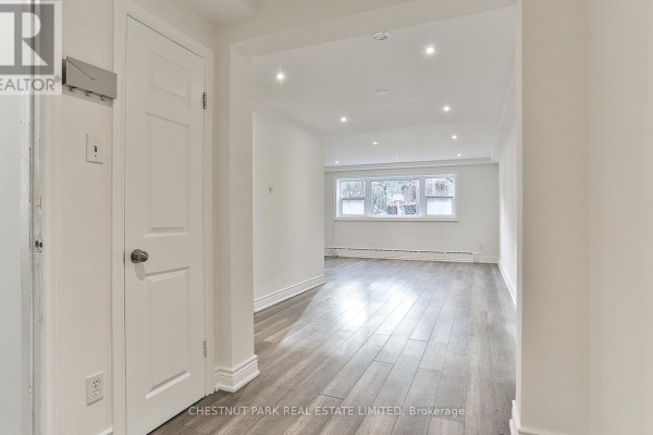 Interior hallway with white door and view into open living area. - 1 - 76 Walmsley Boulevard, Toronto