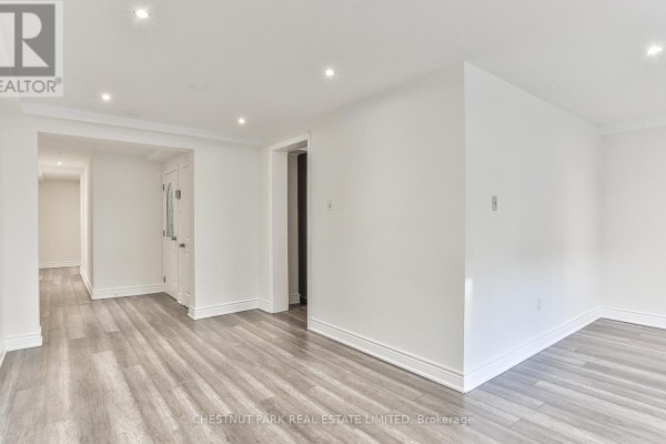 Interior view of white living area with grey wood floors and doorways. - 1 - 76 Walmsley Boulevard, Toronto