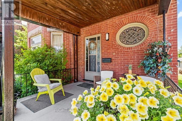 Covered front porch with yellow chairs, flowers, and brick exterior. - 1 - 774 4th Avenue E, Owen Sound