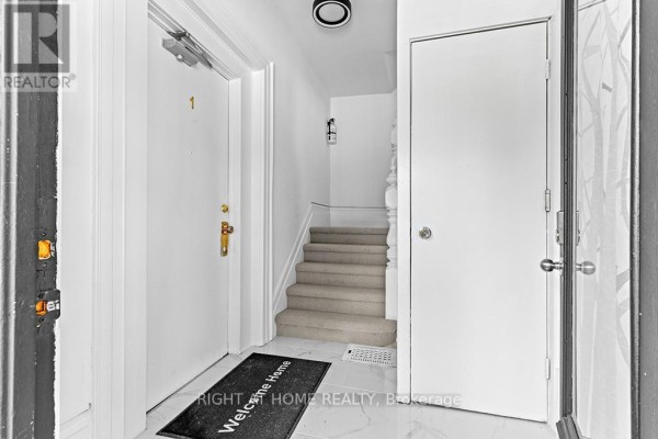 Interior hallway with beige carpeted stairs, white doors, and tile floor. - 1 - 774 4th Avenue E, Owen Sound