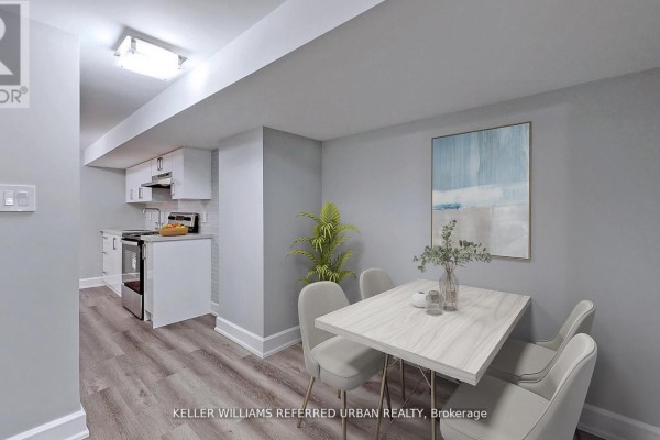 Compact dining area with a table and chairs adjacent to a kitchen, featuring white cabinetry and appliances. - 1 - 783 Dufferin Street, Toronto