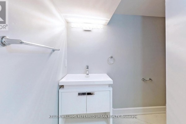 Bathroom with a modern sink and vanity, featuring white tiles and minimalistic design elements. - 1 - 783 Dufferin Street, Toronto