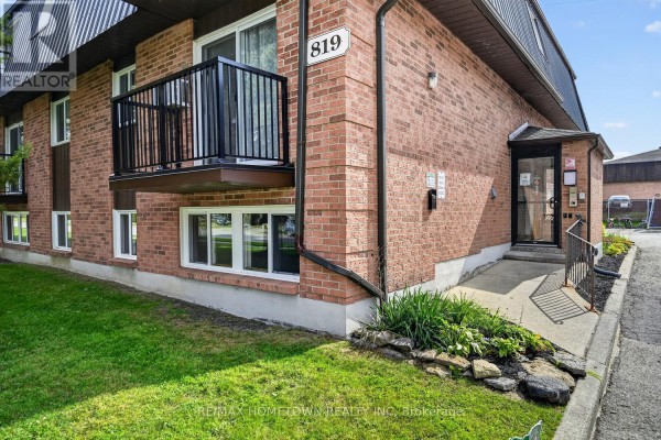 Close-up of the brick exterior of the apartment building with a black railing balcony. - 1 - 819 Macodrum Drive, Brockville