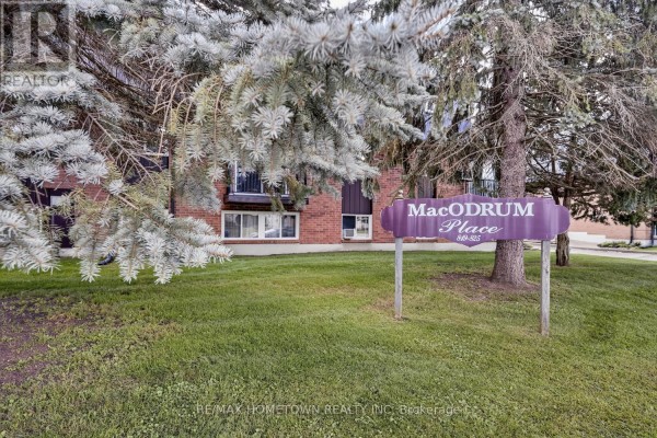 A purple sign reading "MacOdrum Place" in front of the apartment building. - 1 - 819 Macodrum Drive, Brockville