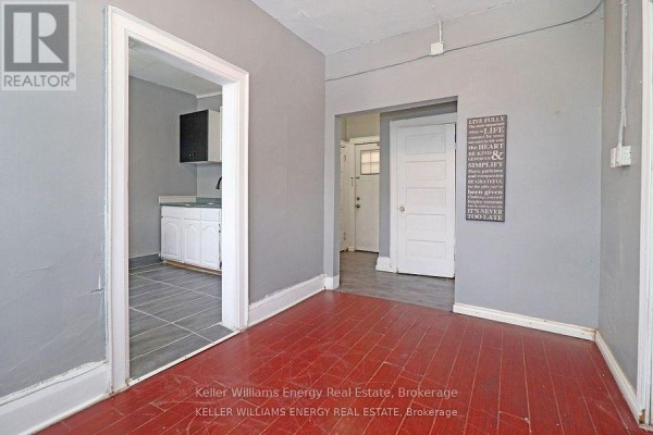 Curved wooden staircase with grey railing and a laundry room door. - 1 - 84 Simcoe Street N, Oshawa