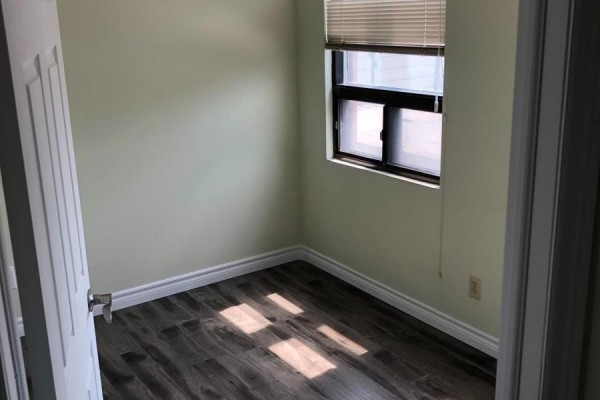 Small room with light green walls, dark wood laminate flooring, and a window with blinds. - 1 - 849 Bathurst Street, Toronto