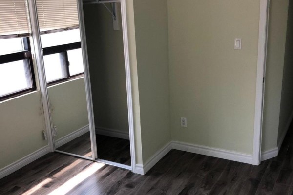 Bedroom with light green walls, dark wood laminate flooring, a window with blinds, and a mirrored closet door. - 1 - 849 Bathurst Street, Toronto