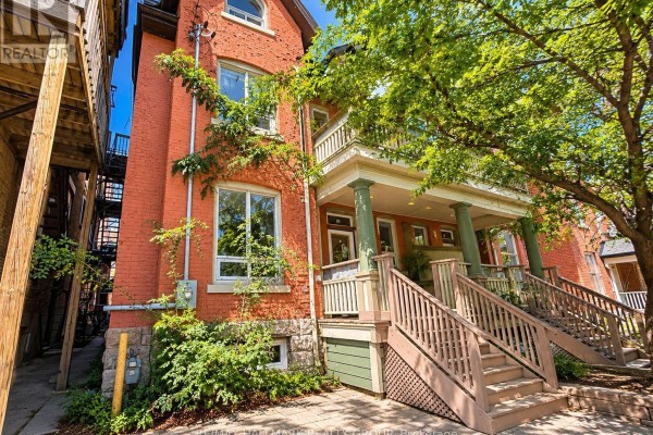 Exterior view of the red brick townhouse from the side, showing multiple windows and balconies. - 1 - 85 Park Avenue, Ottawa
