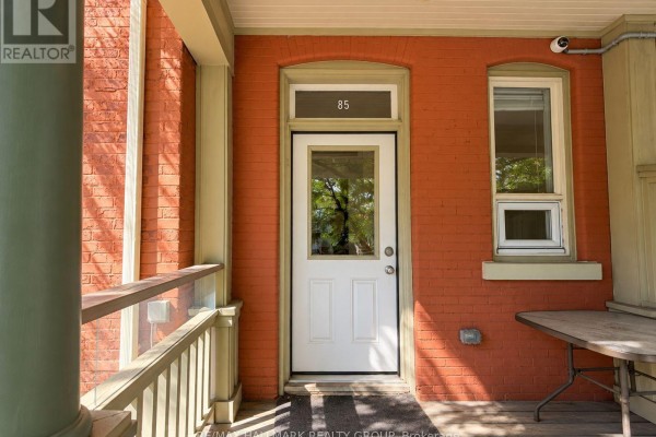 View of the white front door with a window, flanked by red brick walls and a window. - 1 - 85 Park Avenue, Ottawa